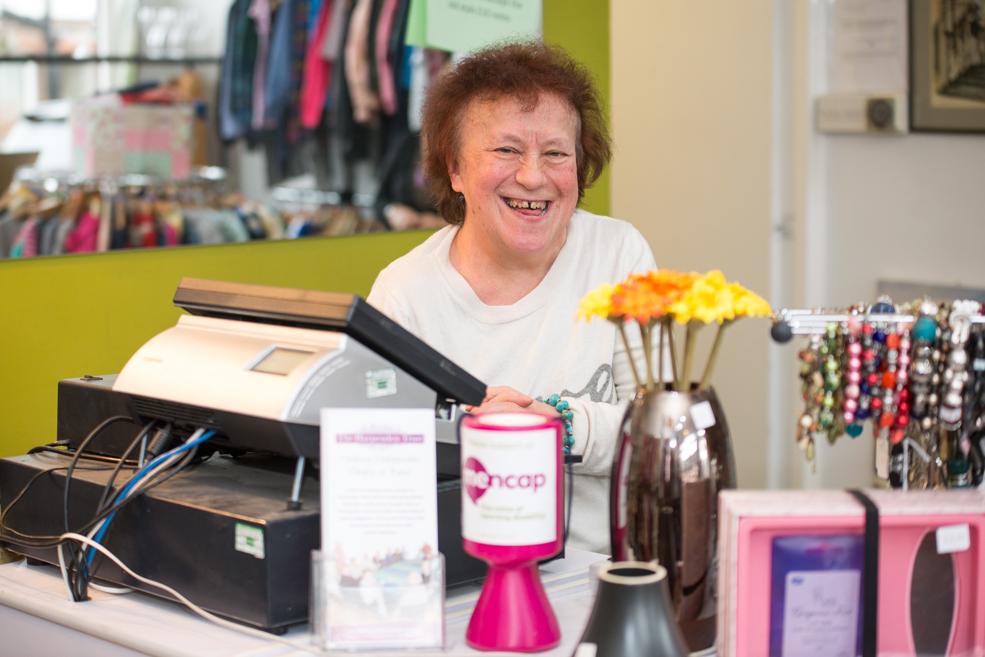 Woman smiling working behind a till | Harpenden Mencap
